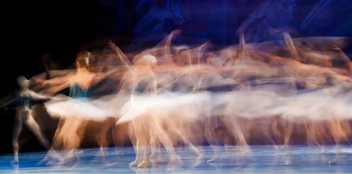 Image of a blurred dancer moving across the stage.